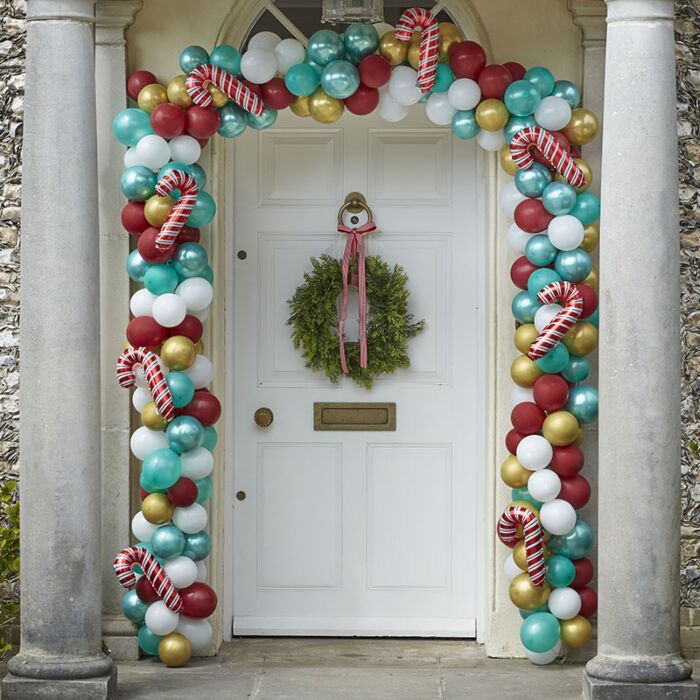 Porta branca decorada com guirlanda e arco de balões coloridos natalinos
