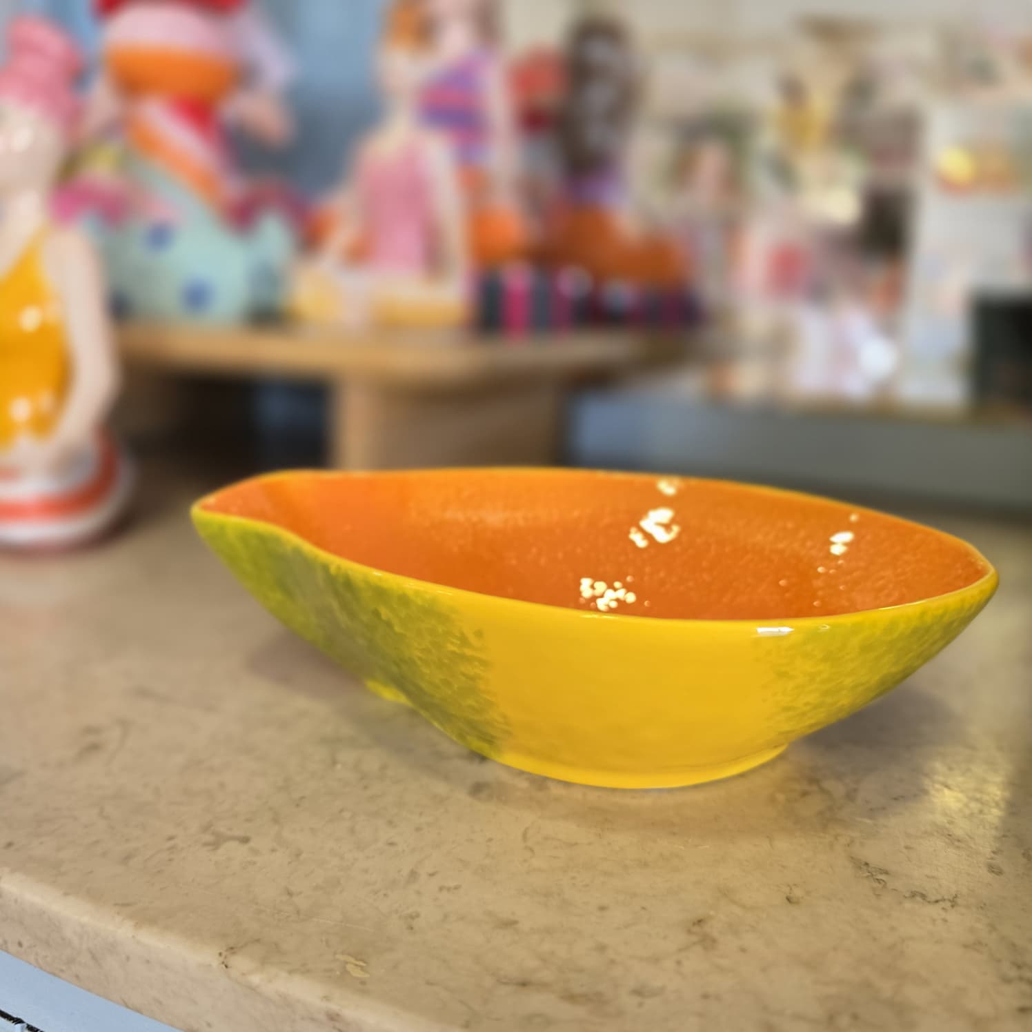 Tigela de cerâmica amarela, verde e laranja sobre superfície de pedra