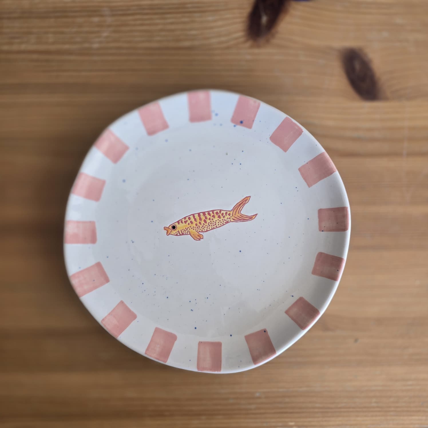 Prato branco com decoração cor-de-rosa e peixe pintado no centro