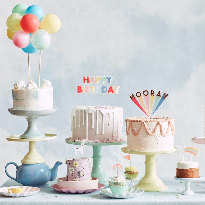 Bolos decorados em suportes pastel com enfeites de aniversário coloridos
