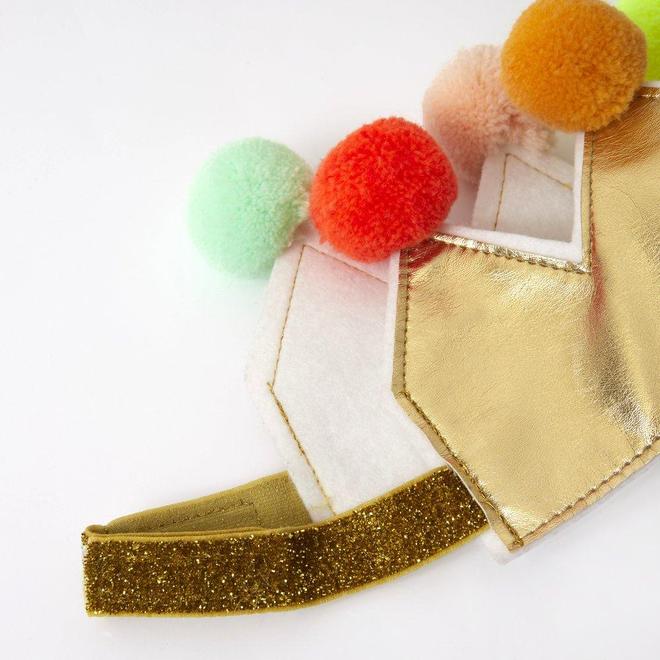 Máscara em tecido dourado e branco com pompons coloridos e velcro dourado