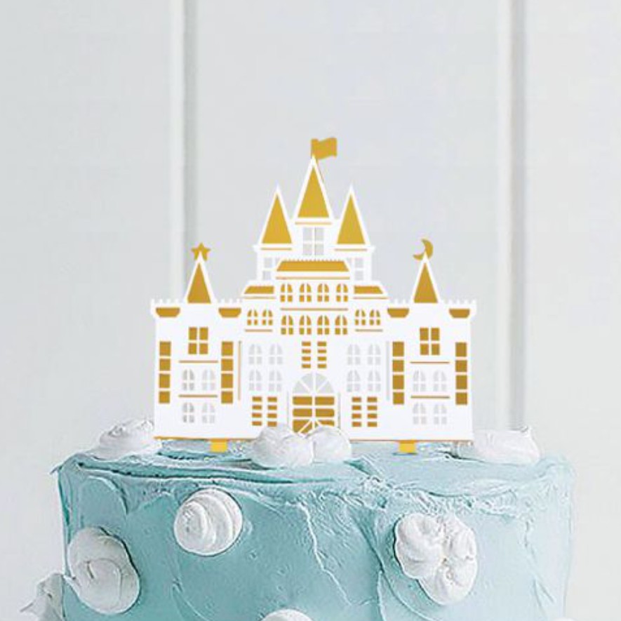 Bolo azul claro com decoração de nuvens brancas e castelo de papel dourado no topo
