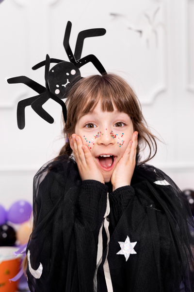 Criança com fantasia preta e adereço de aranha na cabeça