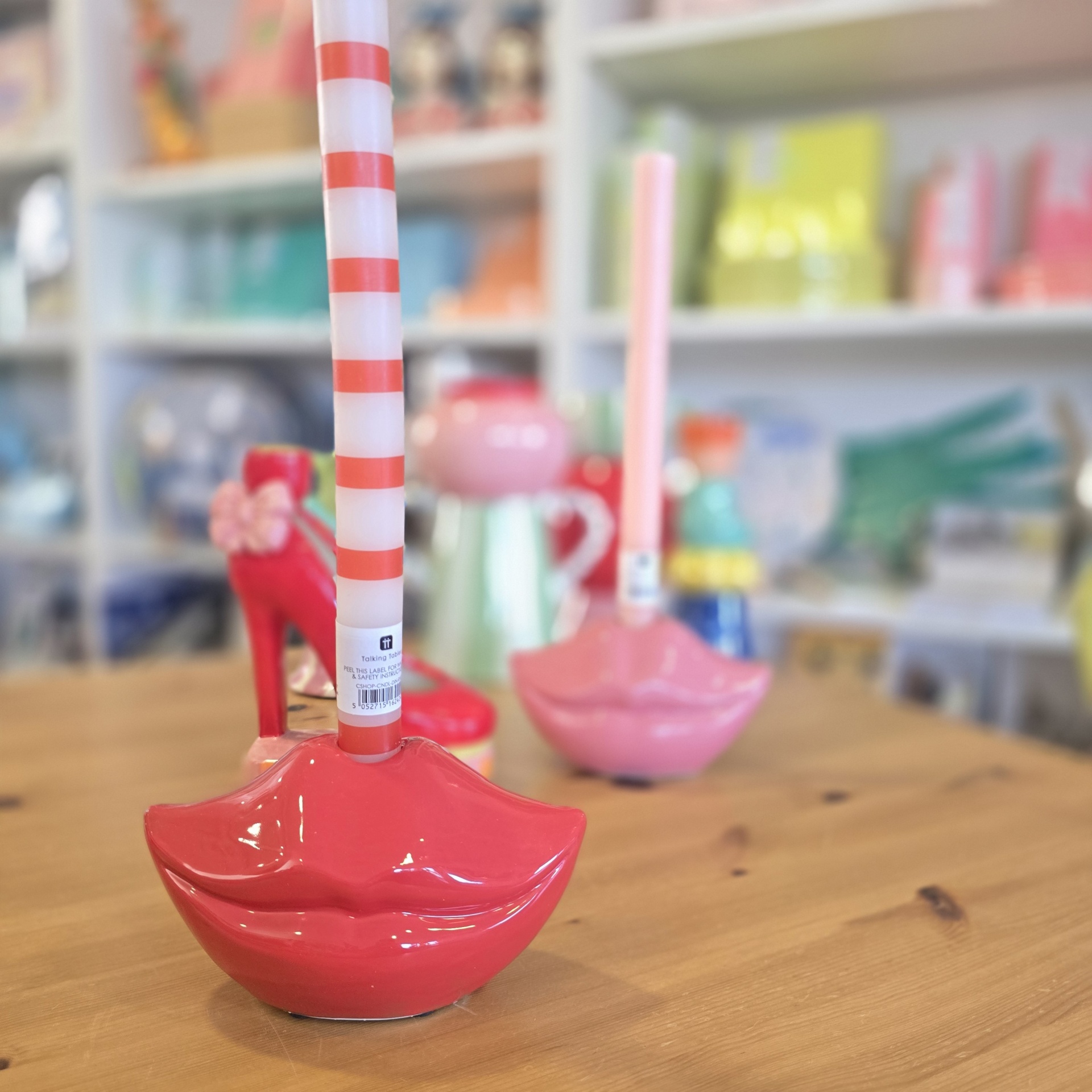 Suportes de lápis em forma de lábios vermelho e rosa com canetas em cima de mesa de madeira