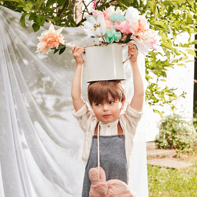Criança com jarro branco e flores ao ar livre
