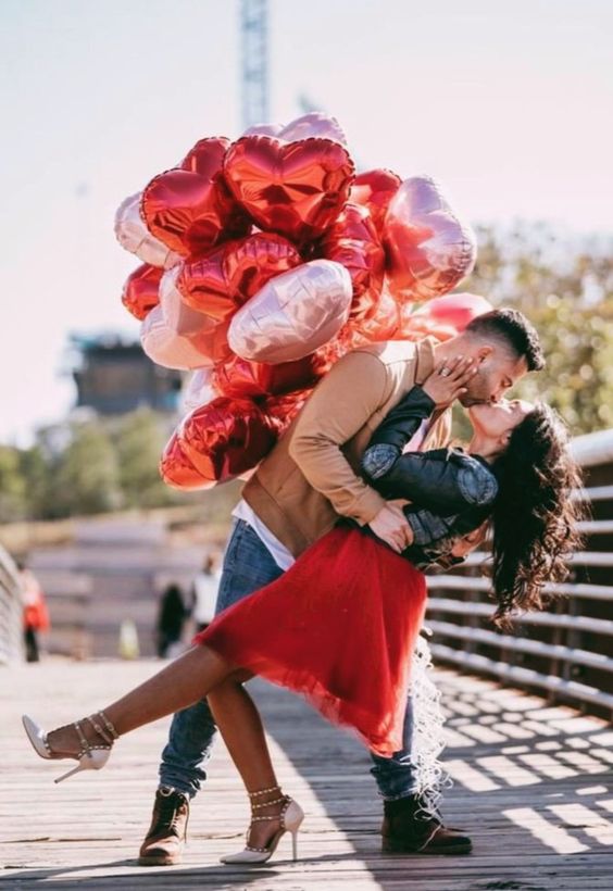 Casal apaixonado com balões de coração num passadiço exterior