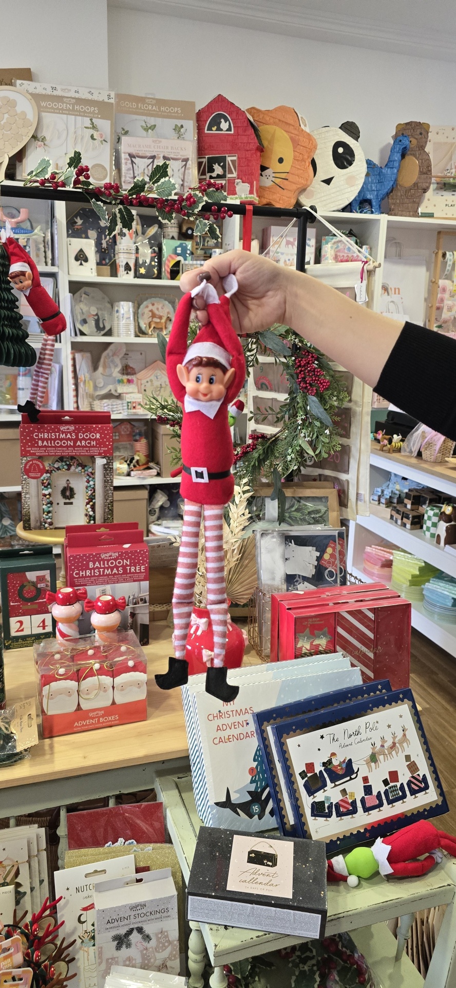 Boneco elfo de Natal vermelho e branco pendurado em loja com decorações natalícias