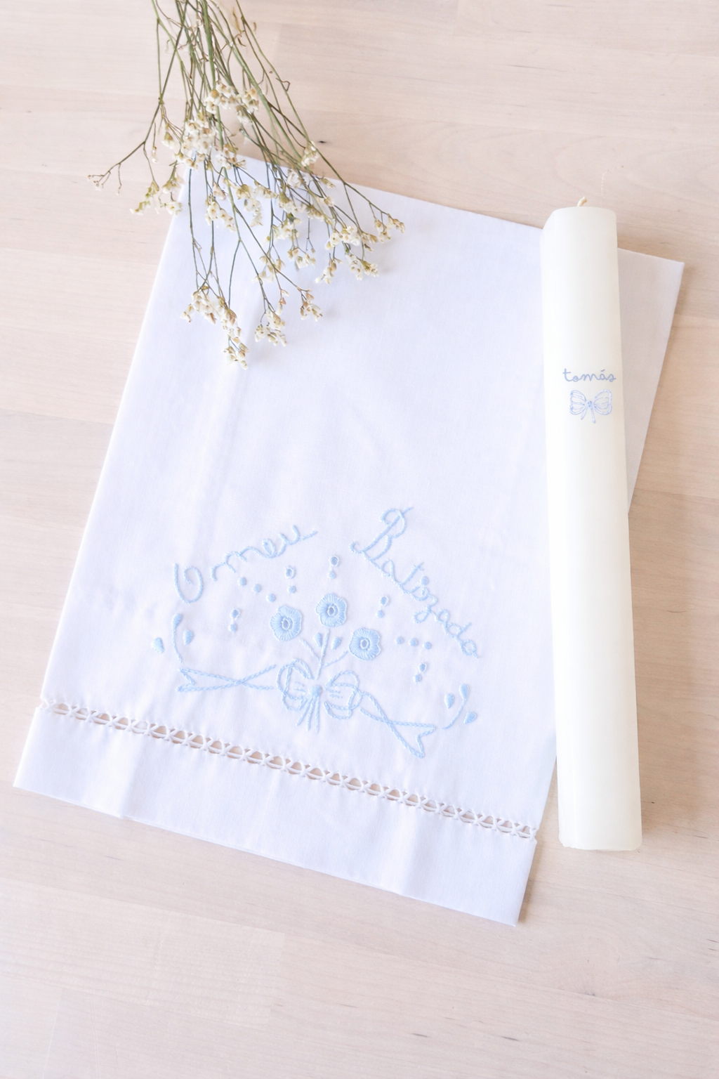 Toalha branca bordada e vela branca com escrita azul