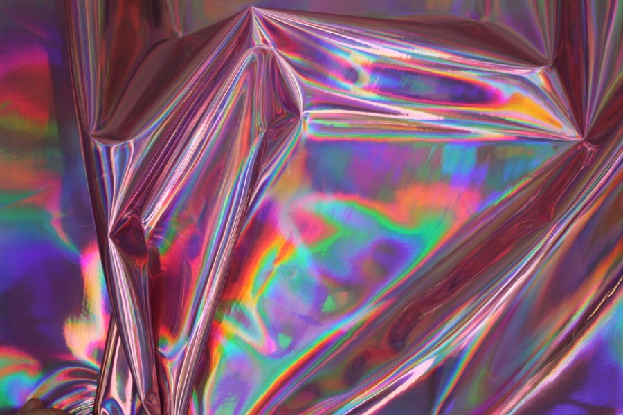 Folha holográfica iridescente com cores variáveis e textura vincada.