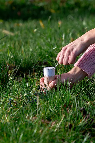 Vela perfumada em copo de vidro branco com tampa de madeira em relva