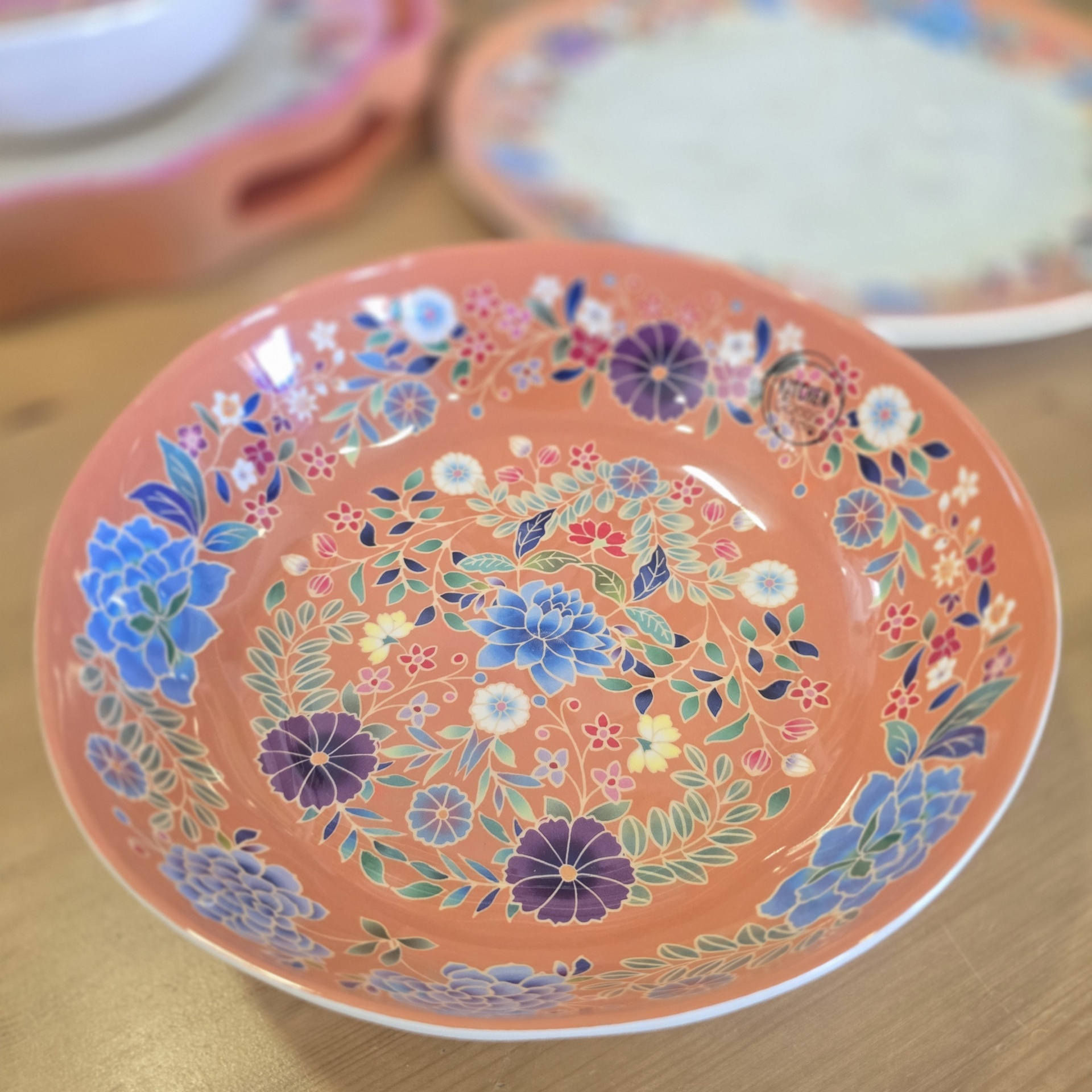 Prato raso cerâmico coral com padrão floral colorido e selo KIRICH