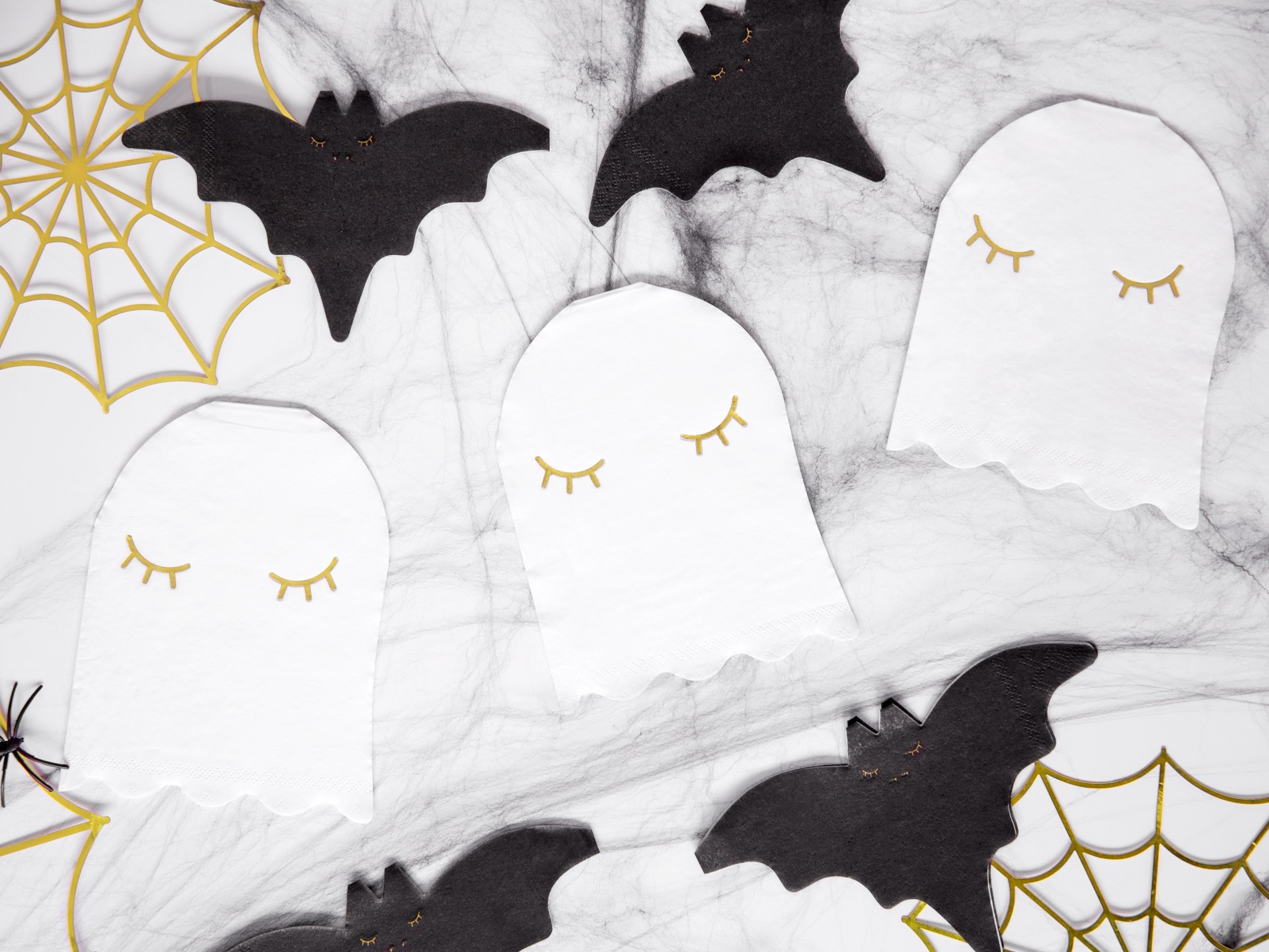 Decoração de Halloween com morcegos pretos e fantasmas brancos sobre fundo com teias de aranha douradas.