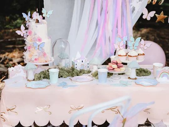 Mesa decorada para festa com bolo, cupcakes, macarons e decoração com borboletas e cores pastel