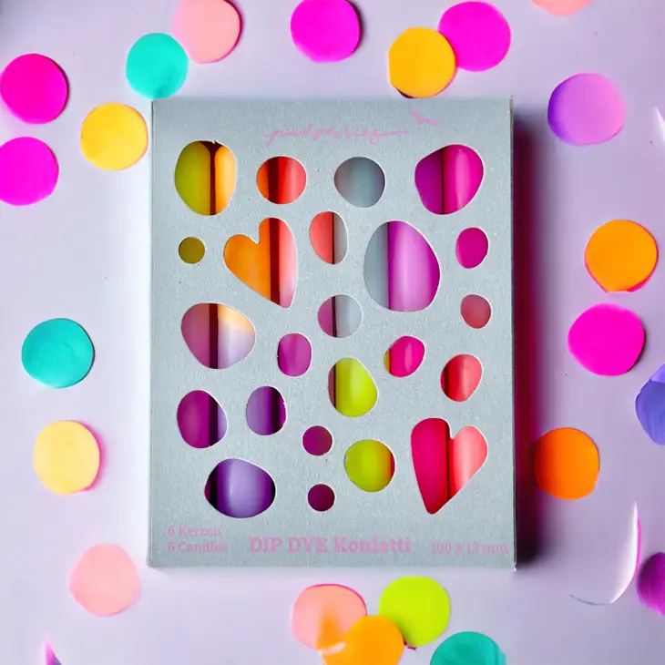 Embalagem branca com lápis de cor visíveis através de recortes, rodeada por confetis coloridos