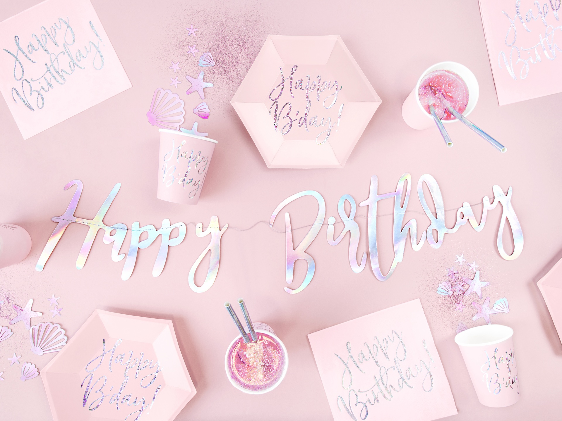 Decoração de festa rosa com copos, caixas hexagonais, guardanapos e letras holográficas com frase Happy Birthday