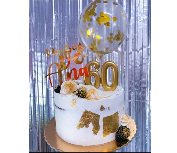 Bolo branco com decoração dourada, números 60 dourados e balão com confetes dourados