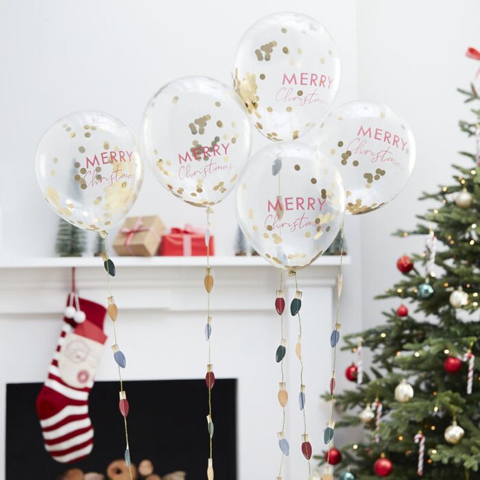Balões transparentes com confetes dourados e texto MERRY Christmas em sala decorada para Natal