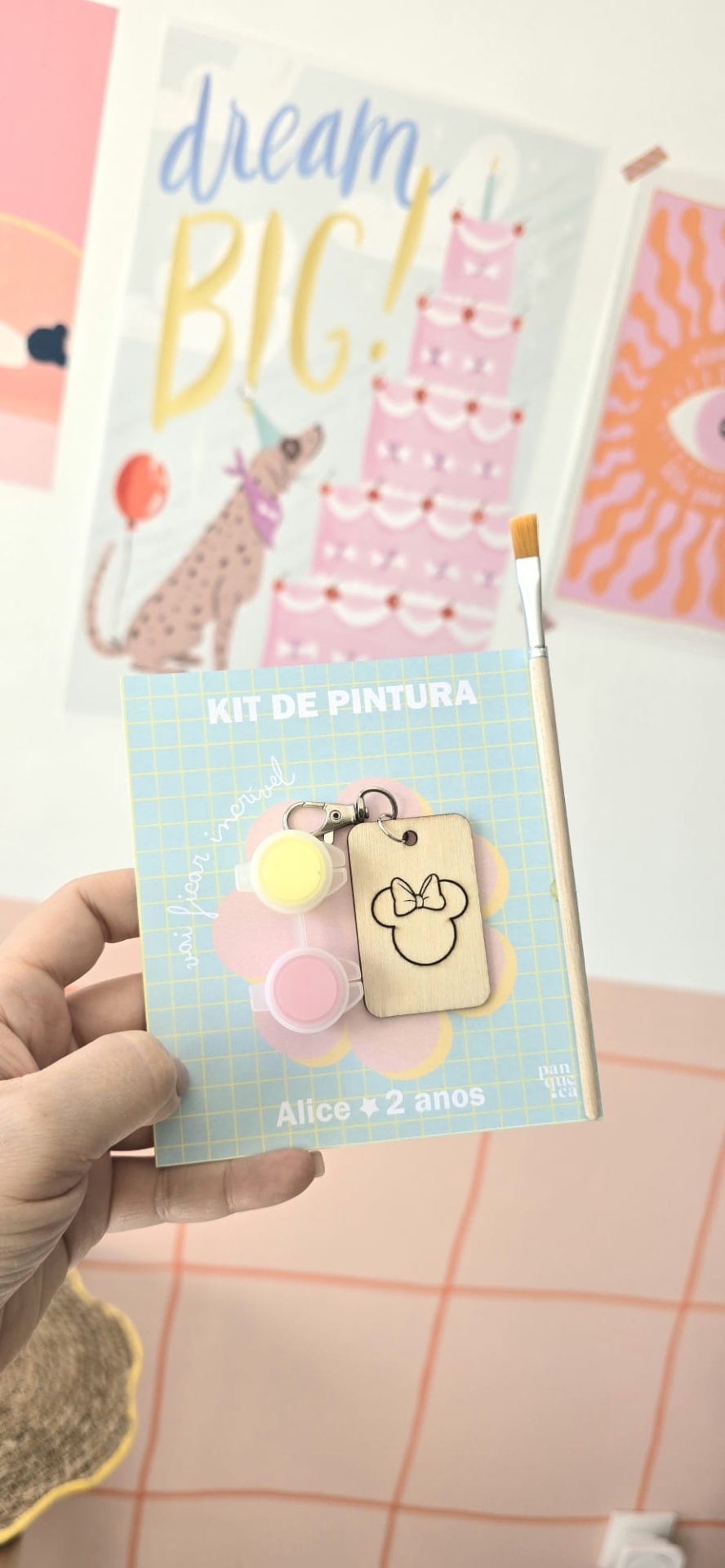 Kit de pintura com tintas, pincel e chaveiro de madeira em embalagem azul com texto.