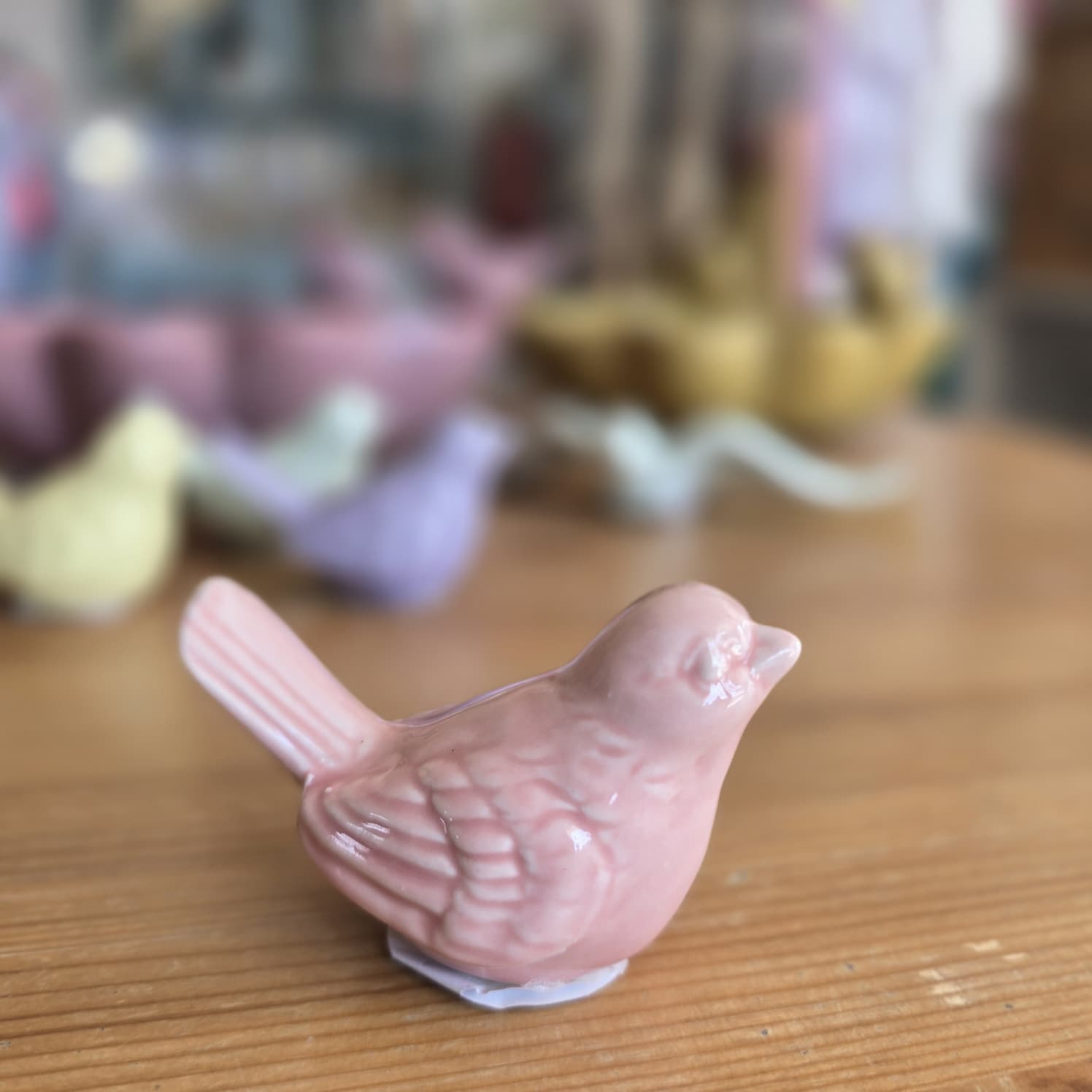Pássaro decorativo cor-de-rosa em cerâmica sobre mesa de madeira