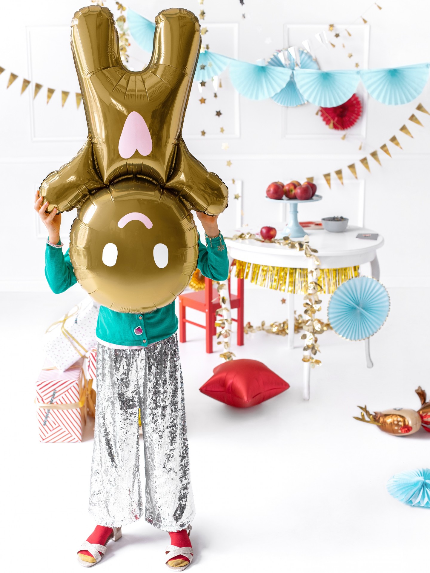 Balão dourado em forma de coelho com decoração festiva no fundo