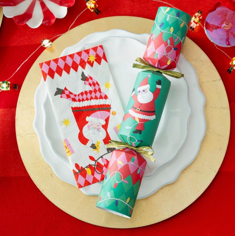 Guardanapo de Natal com estampa de Papai Noel e estalo de Natal colorido sobre pratos e toalha vermelha