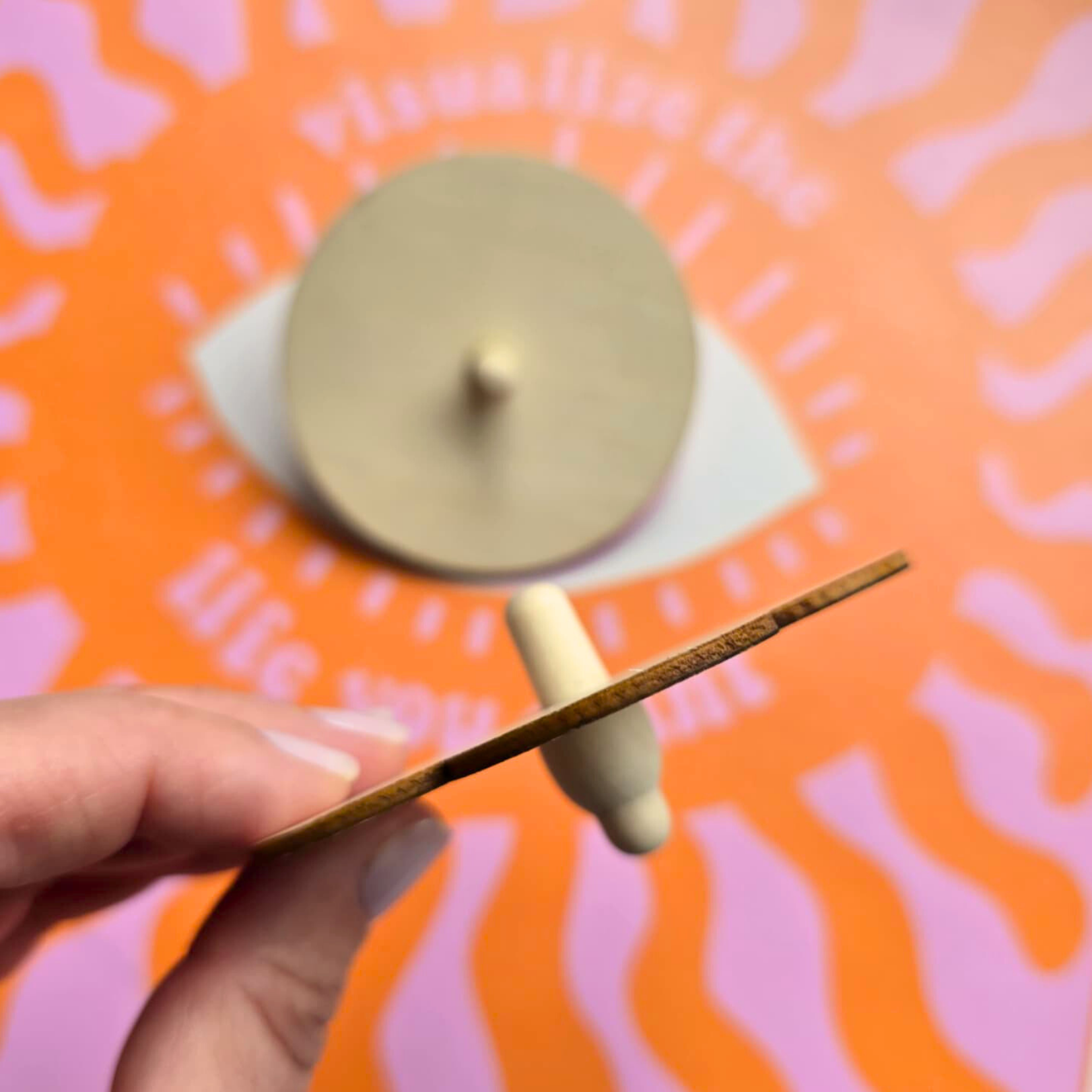 Rolha de cortiça e madeira clara segurada por mão com fundo colorido.