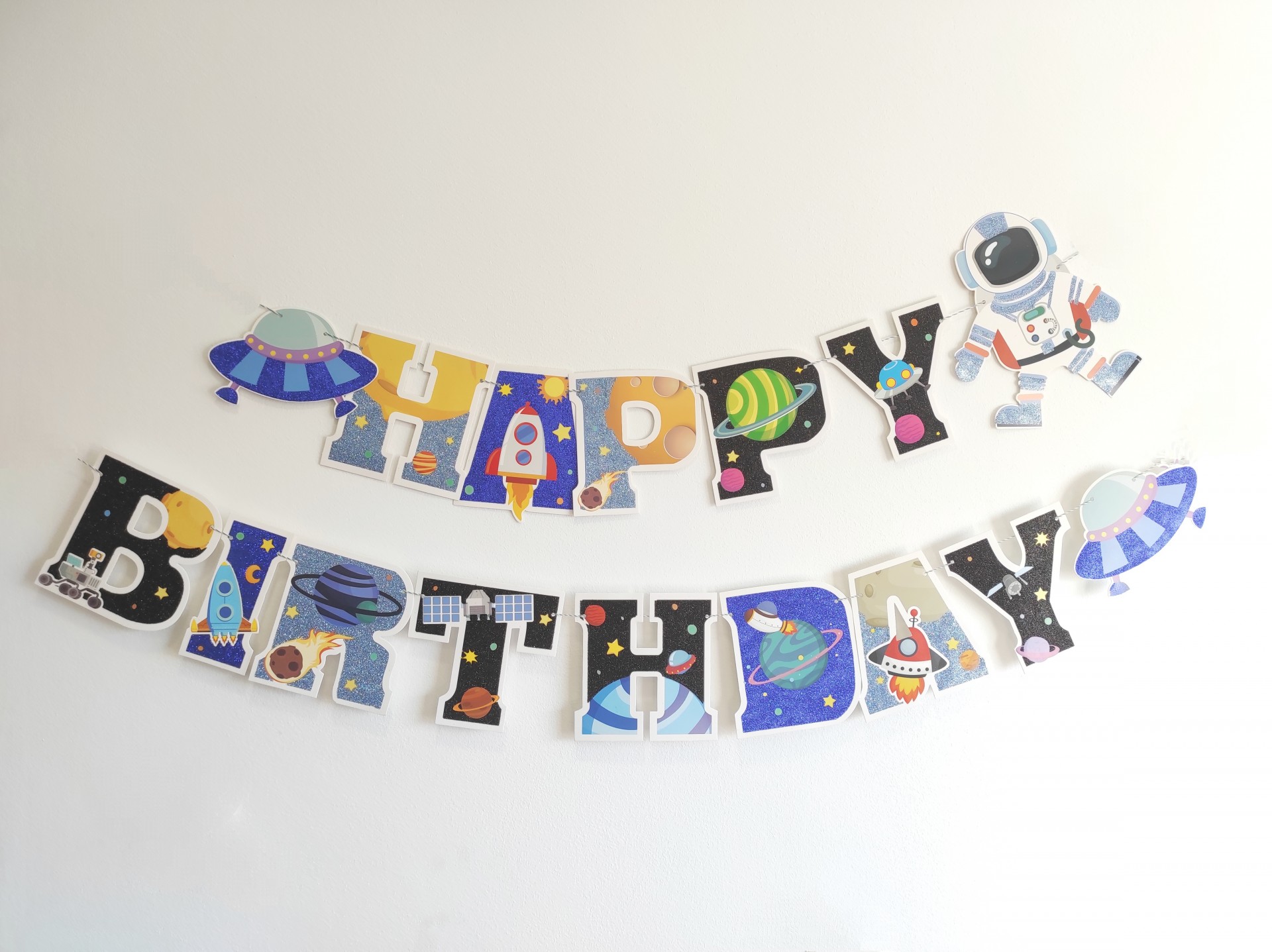 Decoração de festa com letras temáticas espaciais formando HAPPY BIRTHDAY
