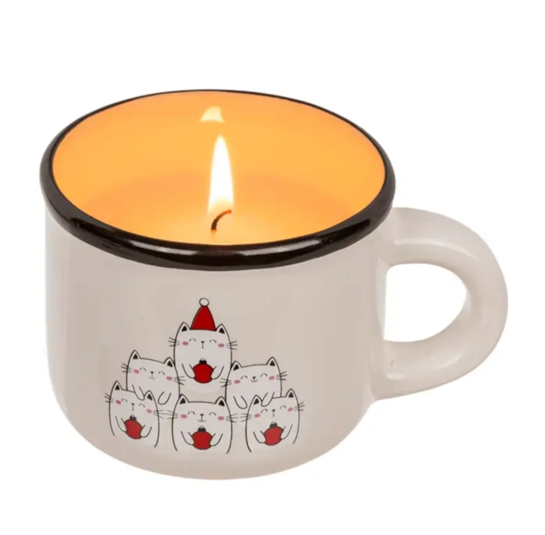 Vela numa chávena branca com desenho de gatos cartoon e interior amarelo