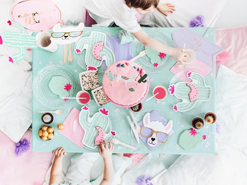 Mesa de festa com decoração de cactos em verde e rosa e crianças à volta