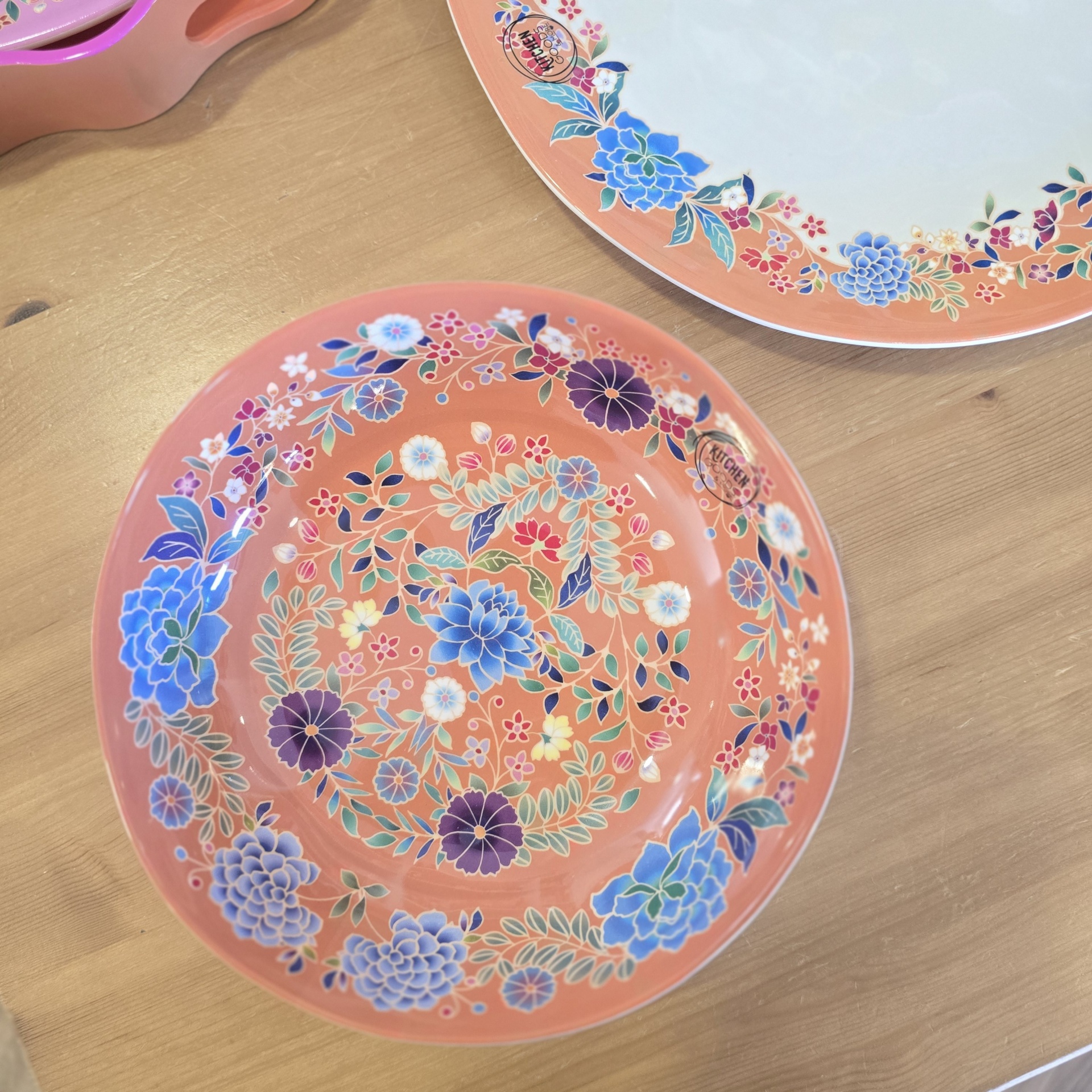 Pratos decorativos em cerâmica com padrão floral colorido em fundo coral