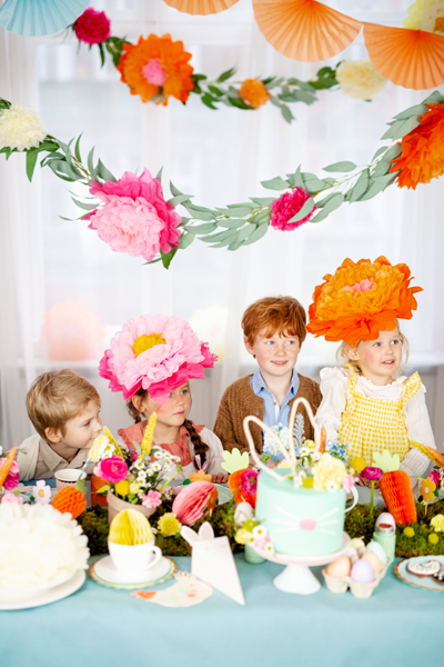 Crianças em festa com decoração colorida e chapéus floridos