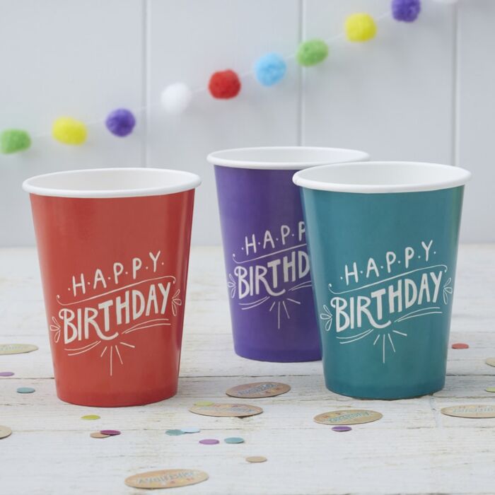 Três copos de papel coloridos com texto 'HAPPY BIRTHDAY'