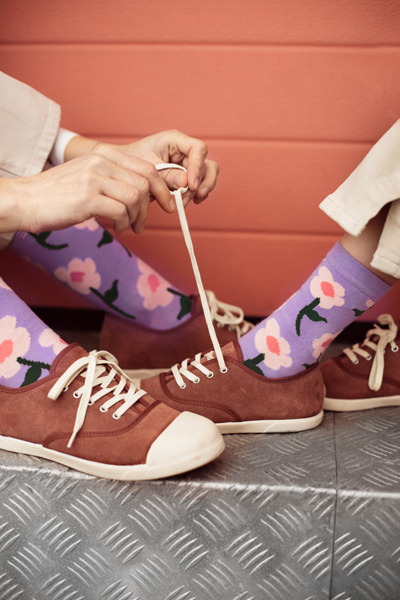 Sapatos castanhos com meias lilás floridas e fundo coral