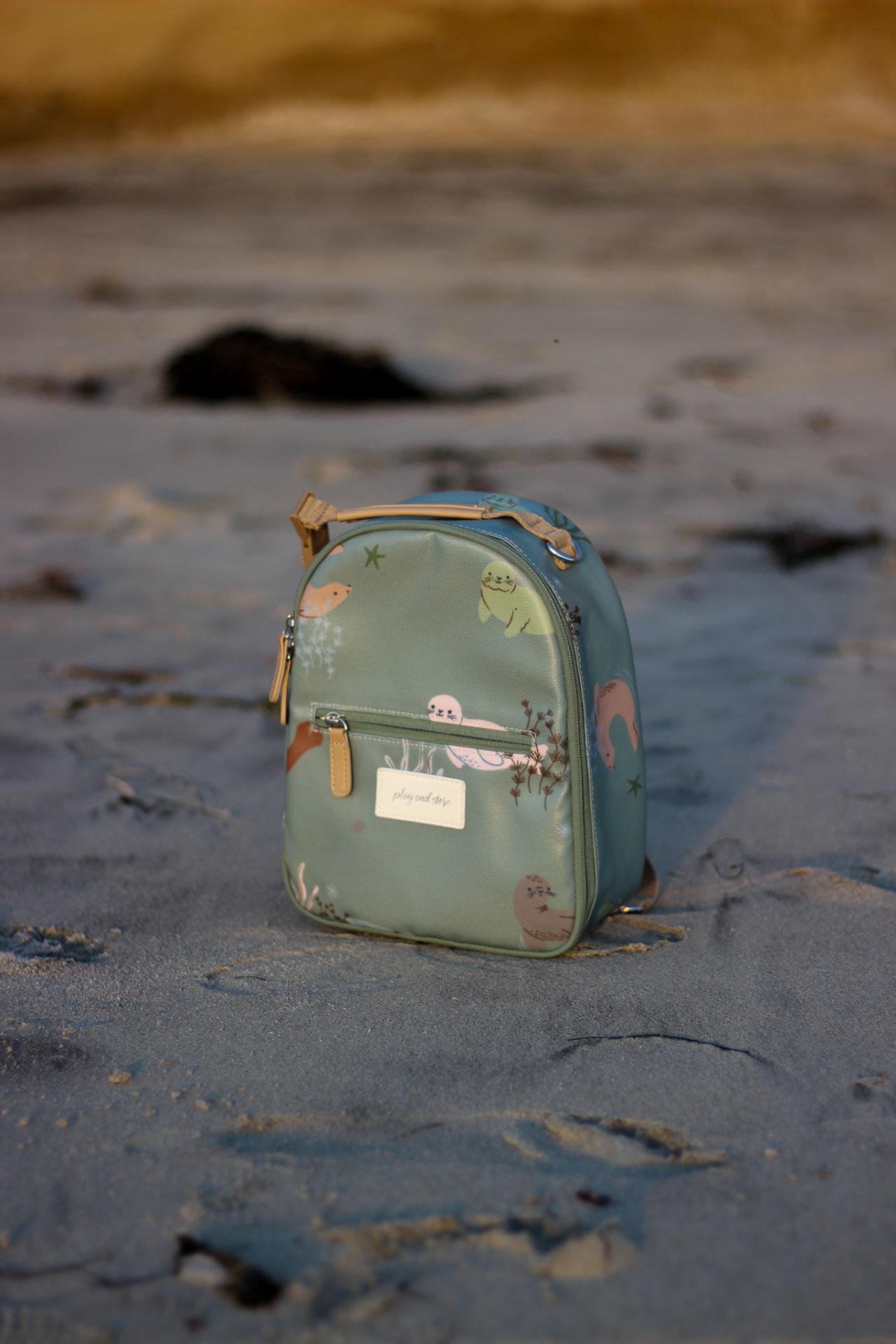 Mochila azul esverdeada com desenhos de animais marinhos na areia