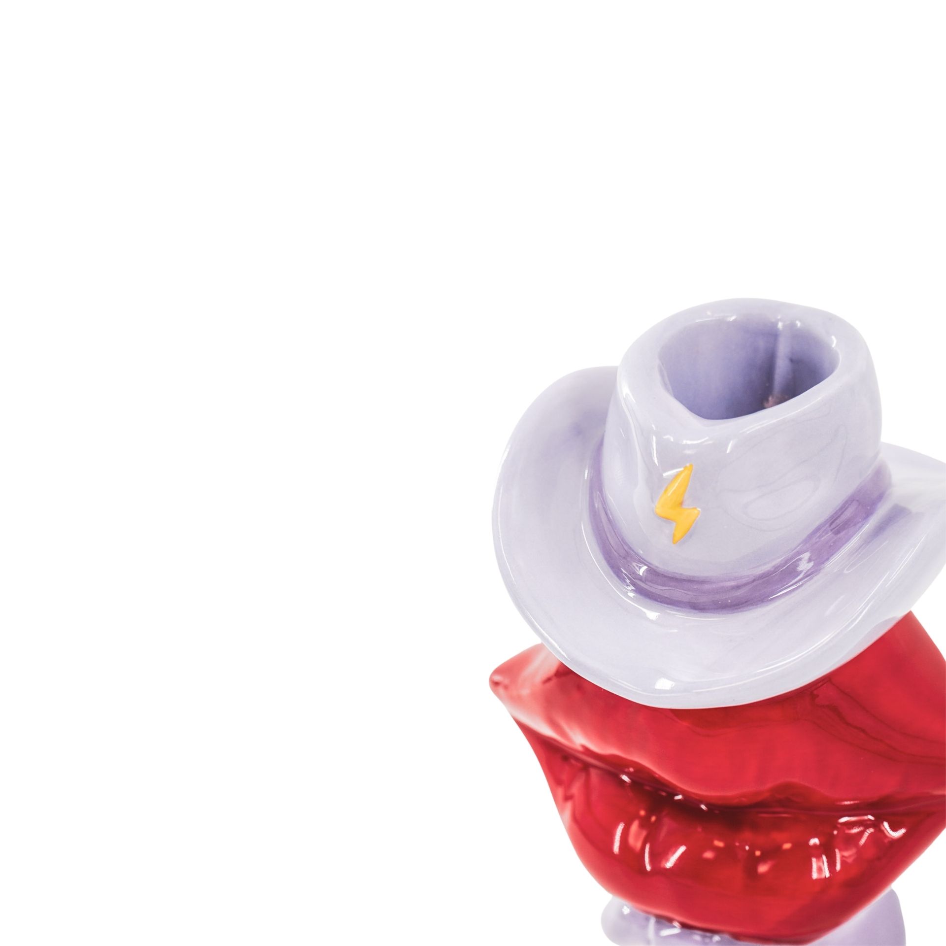 Escultura cerâmica lábios vermelhos chapéu lilás com símbolo de raio