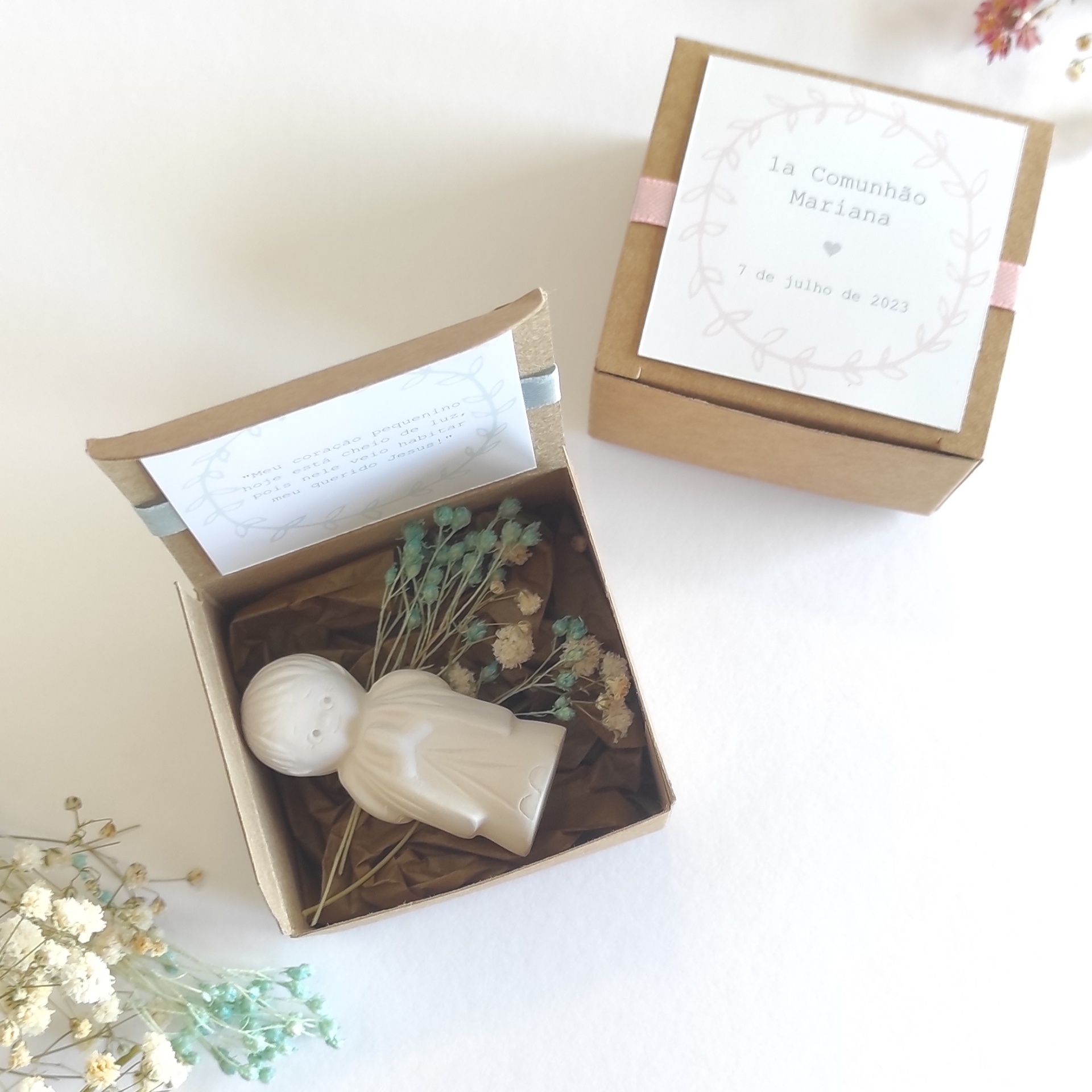 Caixa de presente kraft com figura cerâmica branca, flores secas e etiqueta de 1ª Comunhão