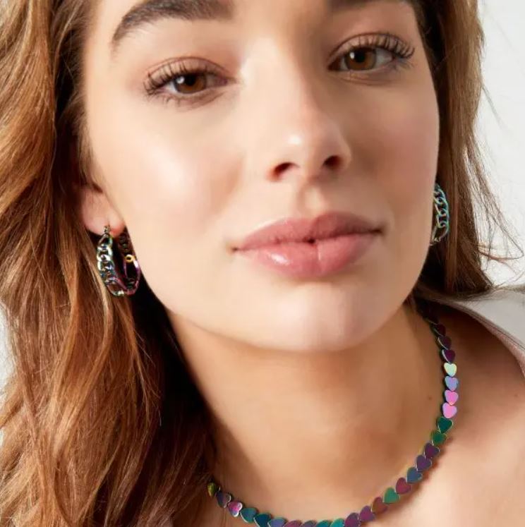 Colar e brincos iridescentes com padrão de corações usados por mulher