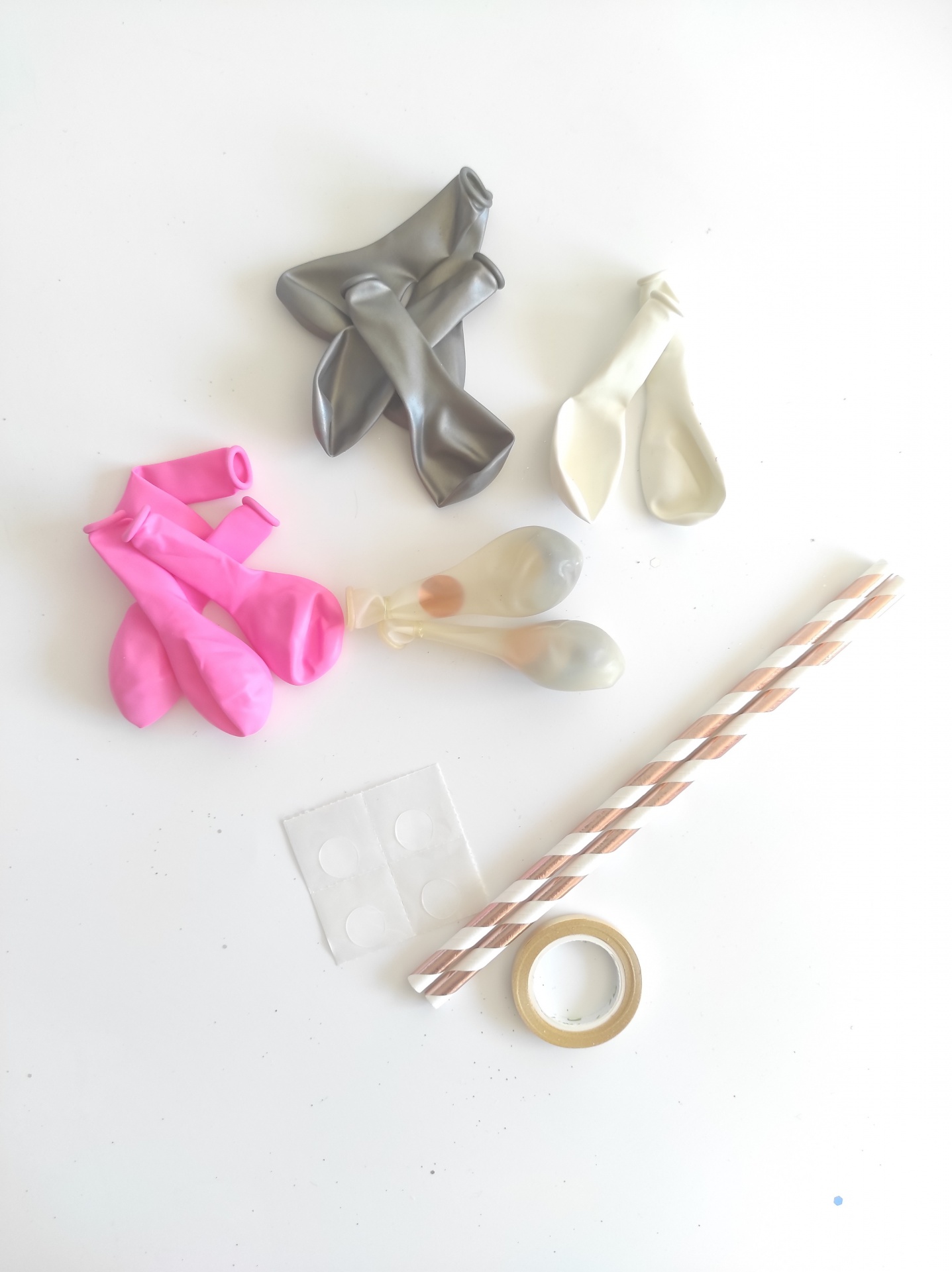 Balões coloridos, canudos risca branca e rosa, fita adesiva e adesivos dupla face sobre fundo branco