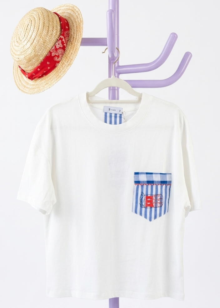 T-shirt branca com bolso às riscas azuis e um chapéu de palha com lenço vermelho