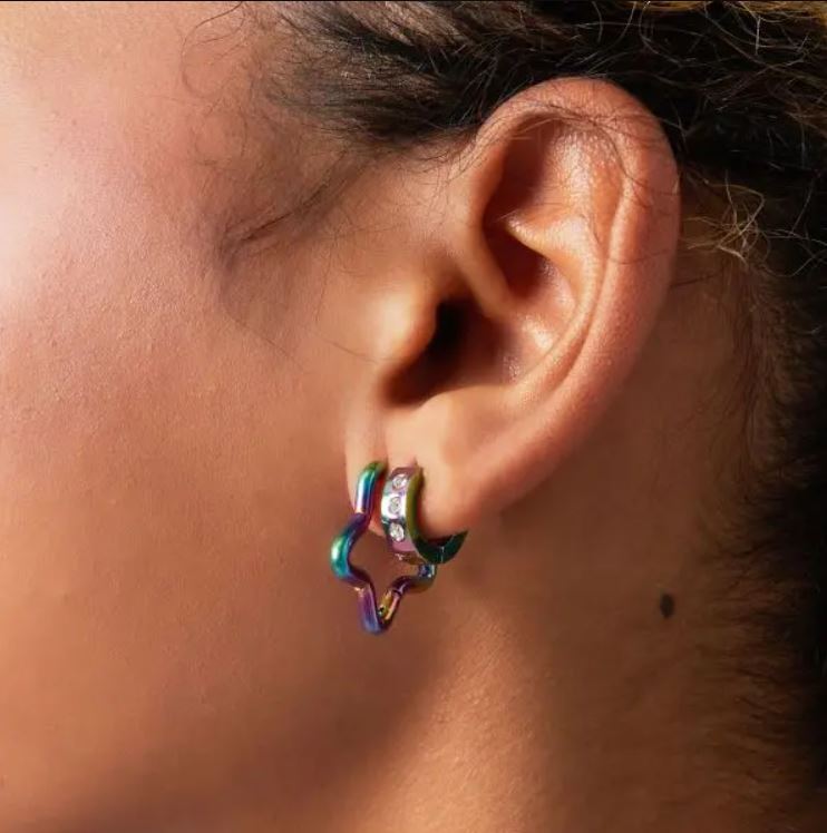 Brinco em forma de estrela metálica iridescente na orelha.