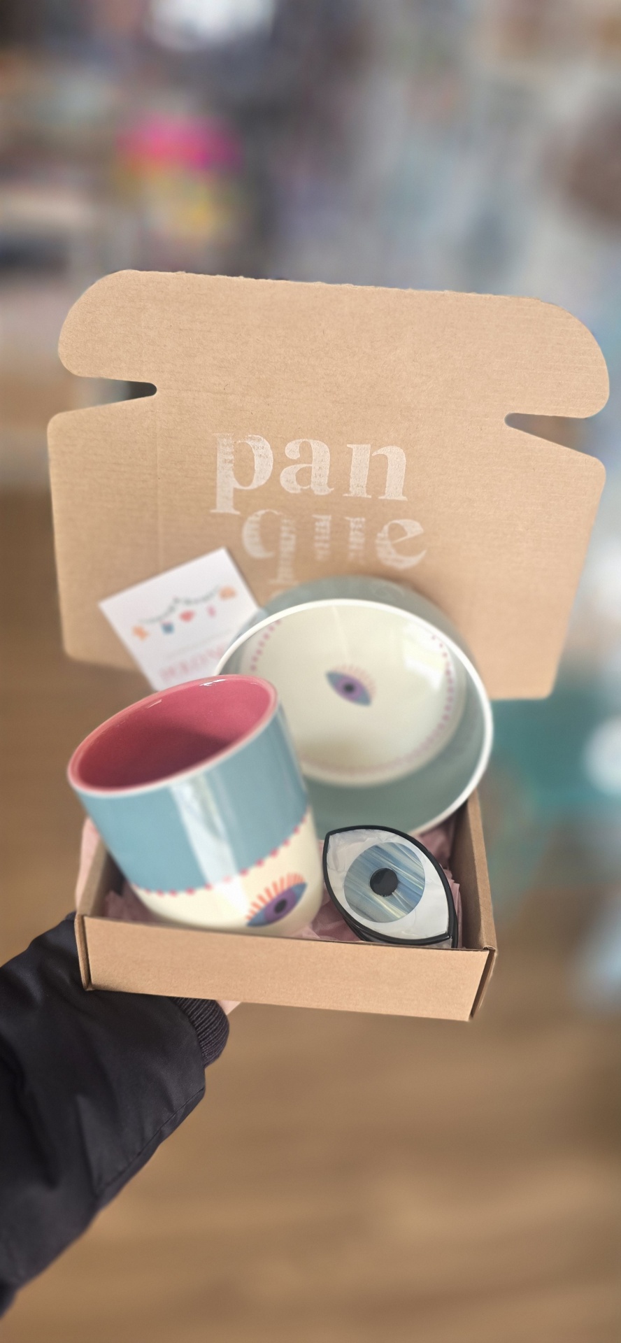 Conjunto de caneca, prato e objeto em forma de olho dentro de caixa de cartão