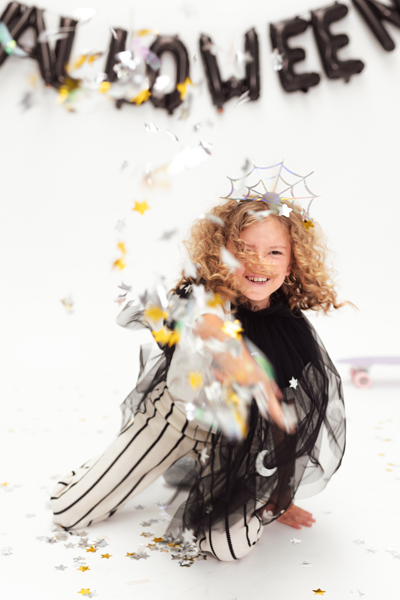 Criança com fantasia de Halloween com capa preta e aranha na cabeça