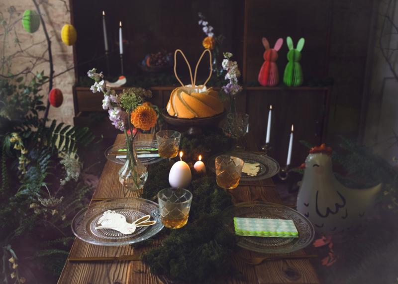 Mesa decorada com bolo, velas e figuras de coelho para festa de primavera