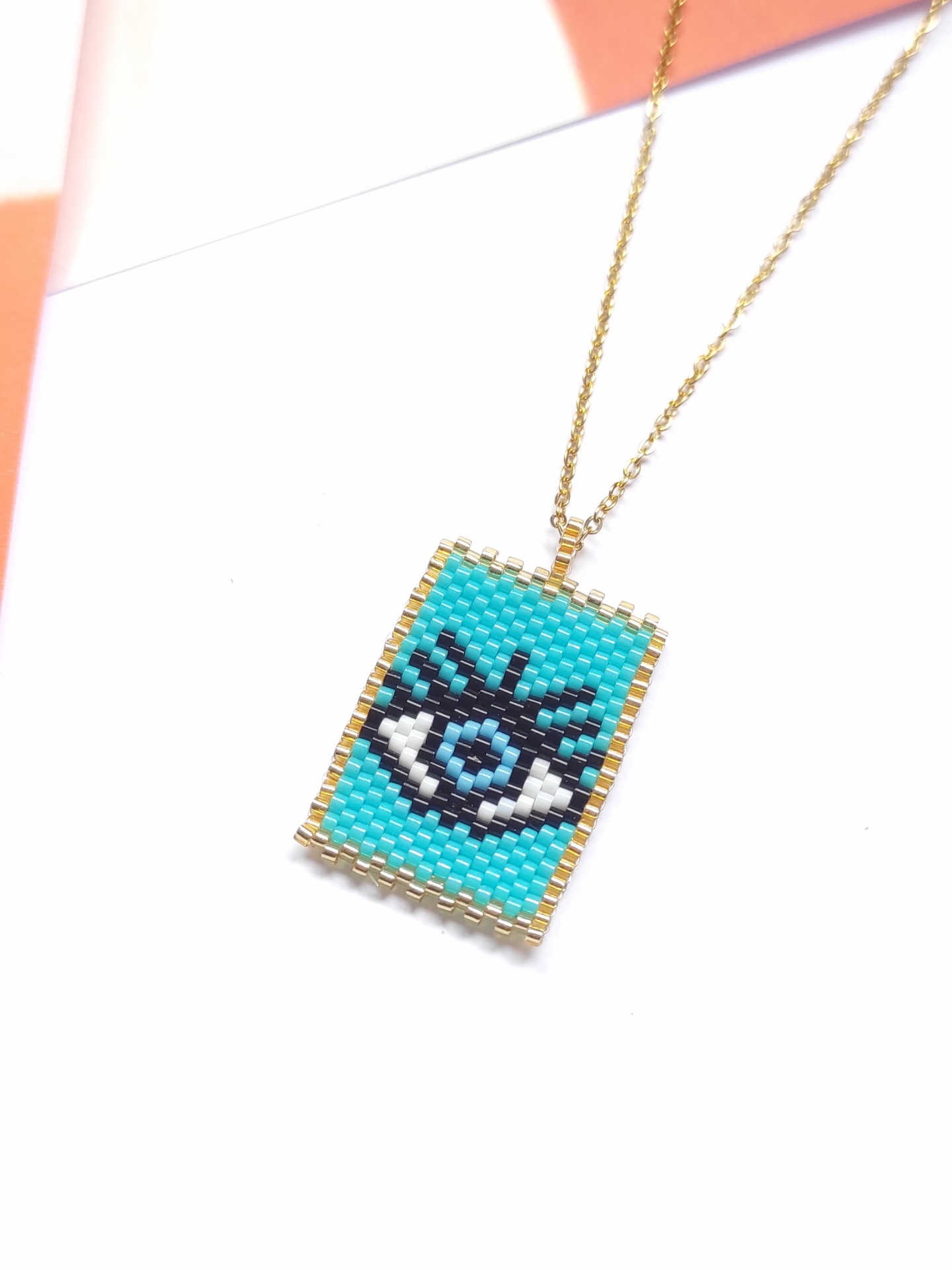 Colar com pendente retangular azul com desenho de olho em contas