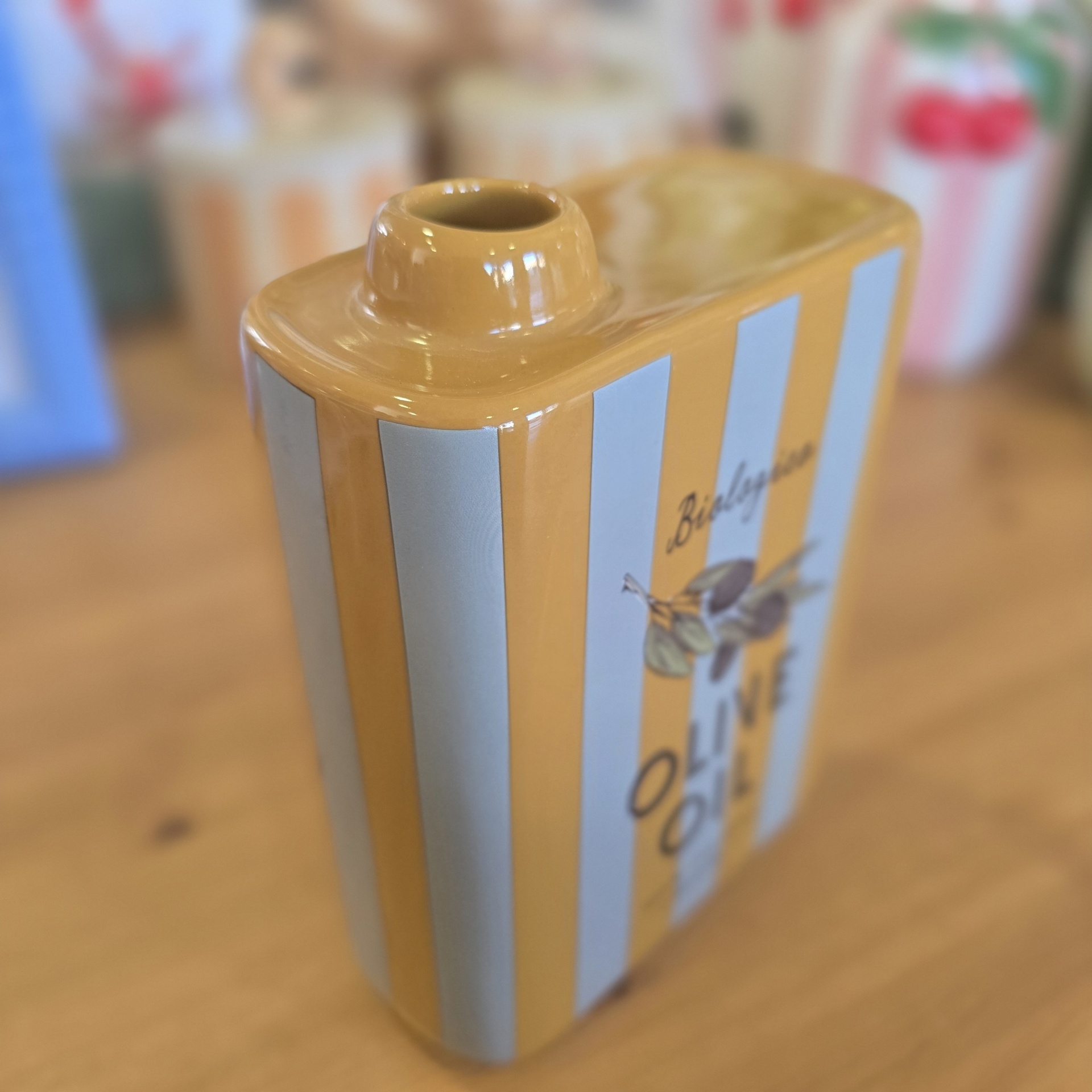 Recipiente cerâmico riscas amarelas e brancas com texto Biologico OLIVE OIL e ramo de oliveira