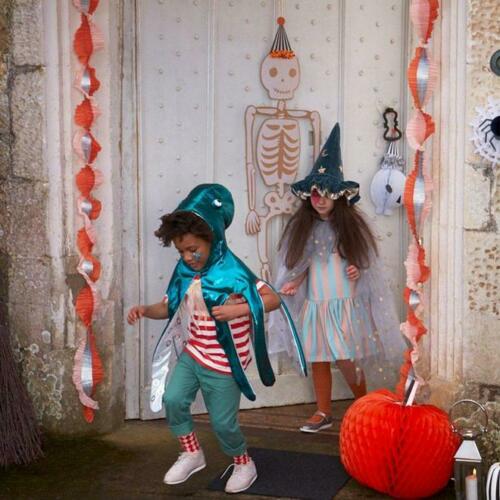 Crianças fantasiadas de Halloween com decoração de esqueleto e abóbora na porta