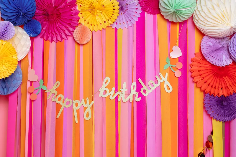 Decoração de festa colorida com círculos de papel e faixa 'happy birthday'