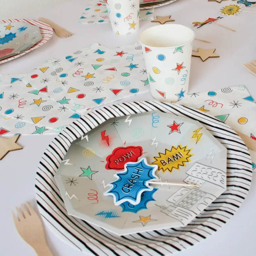 Mesa de festa com pratos descartáveis decorados e copos de papel coloridos
