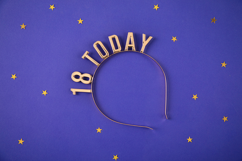 Tiara dourada com texto 18 TODAY sobre fundo azul com estrelas douradas