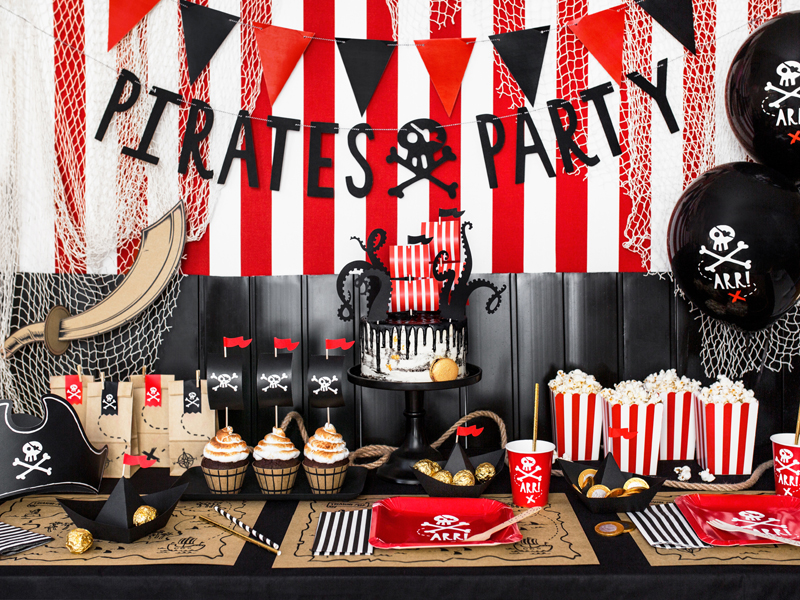 Mesa de festa temática de piratas com decoração vermelha, preta e branca, bolo, cupcakes, balões, copos e bandeira PIRATES PARTY